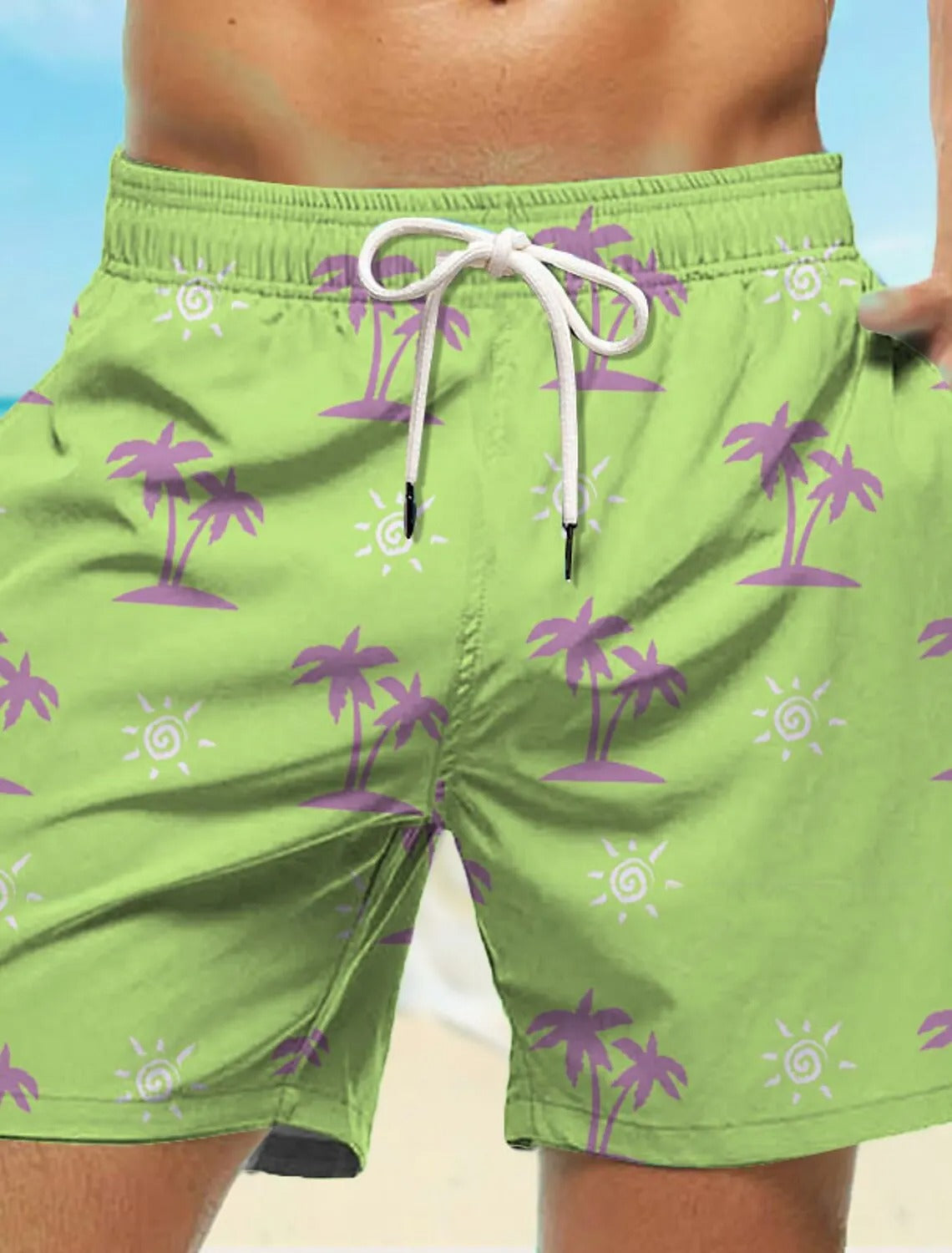 Grüne Badeshorts mit lila Palmenmuster, Herrenmode, Strandbekleidung, Sommertrends.
