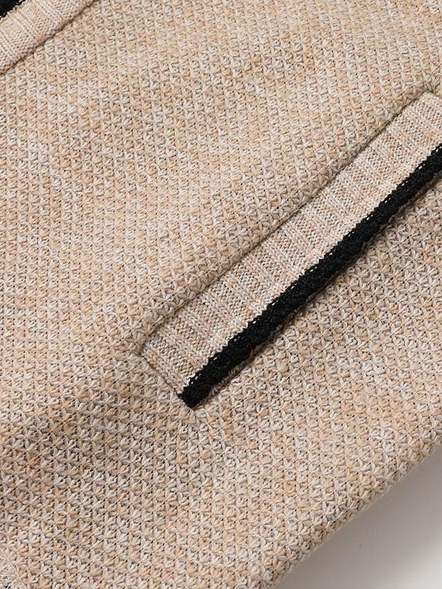 Beige Jacke mit feinem Webmuster und schwarzem Akzent an der Tasche. Elegantes Design, ideal für stilvolle Herbst- und Wintermode.